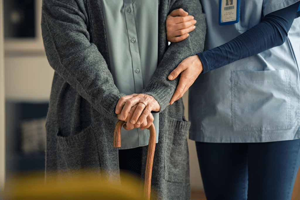 Closeup of hands of nurse with senior adult walking with cane