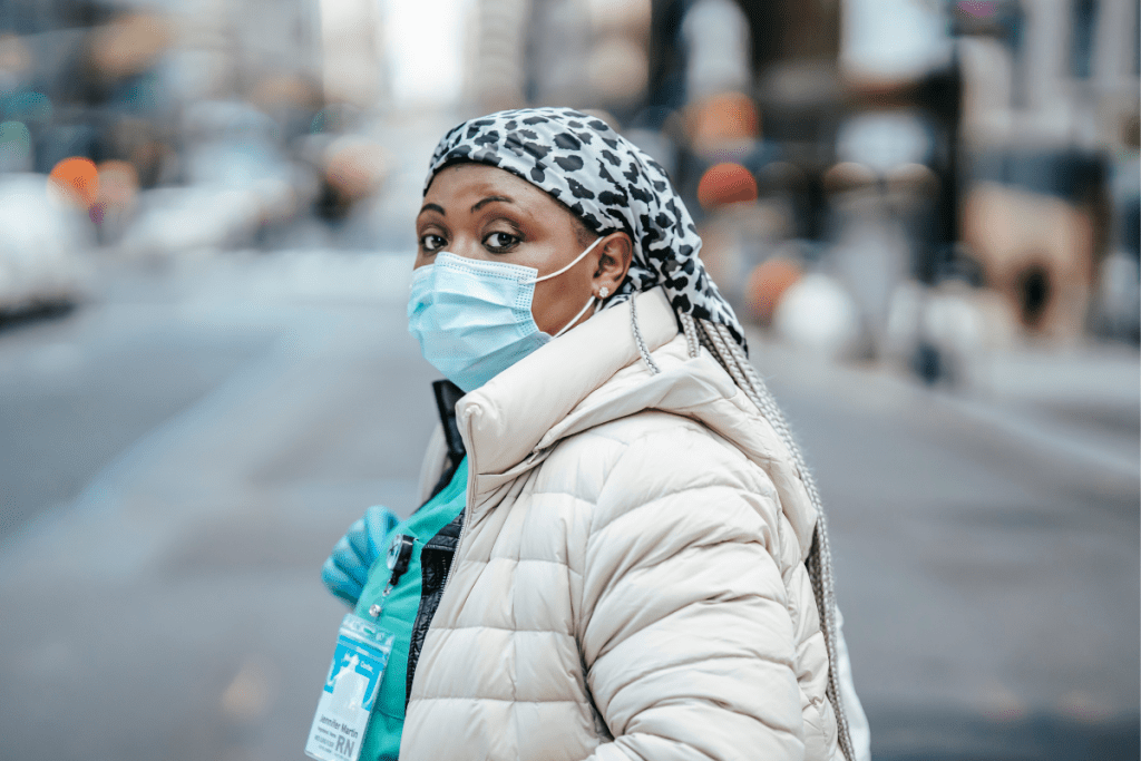 Nurse in mask crossing road in city