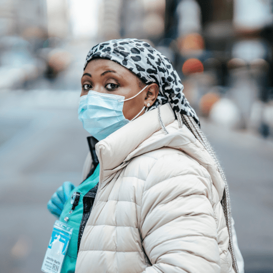 Nurse in mask crossing road in city