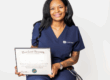 Nurse in blue scrubs holding graduation diploma